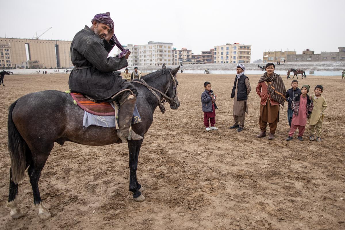 Jinetes afganos compiten en un deporte tradicional de Asia Central, en el que los jugadores montados a caballo intentan colocar una bolsa que se asemeja a un cadáver de cabra en una portería