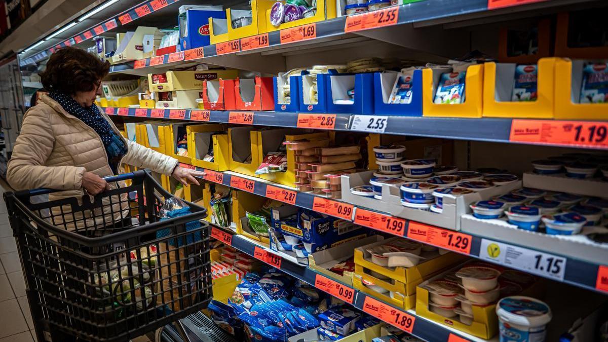 Una mujer compra en un supermercado en el primer día de la rebaja del IVA alimentario.