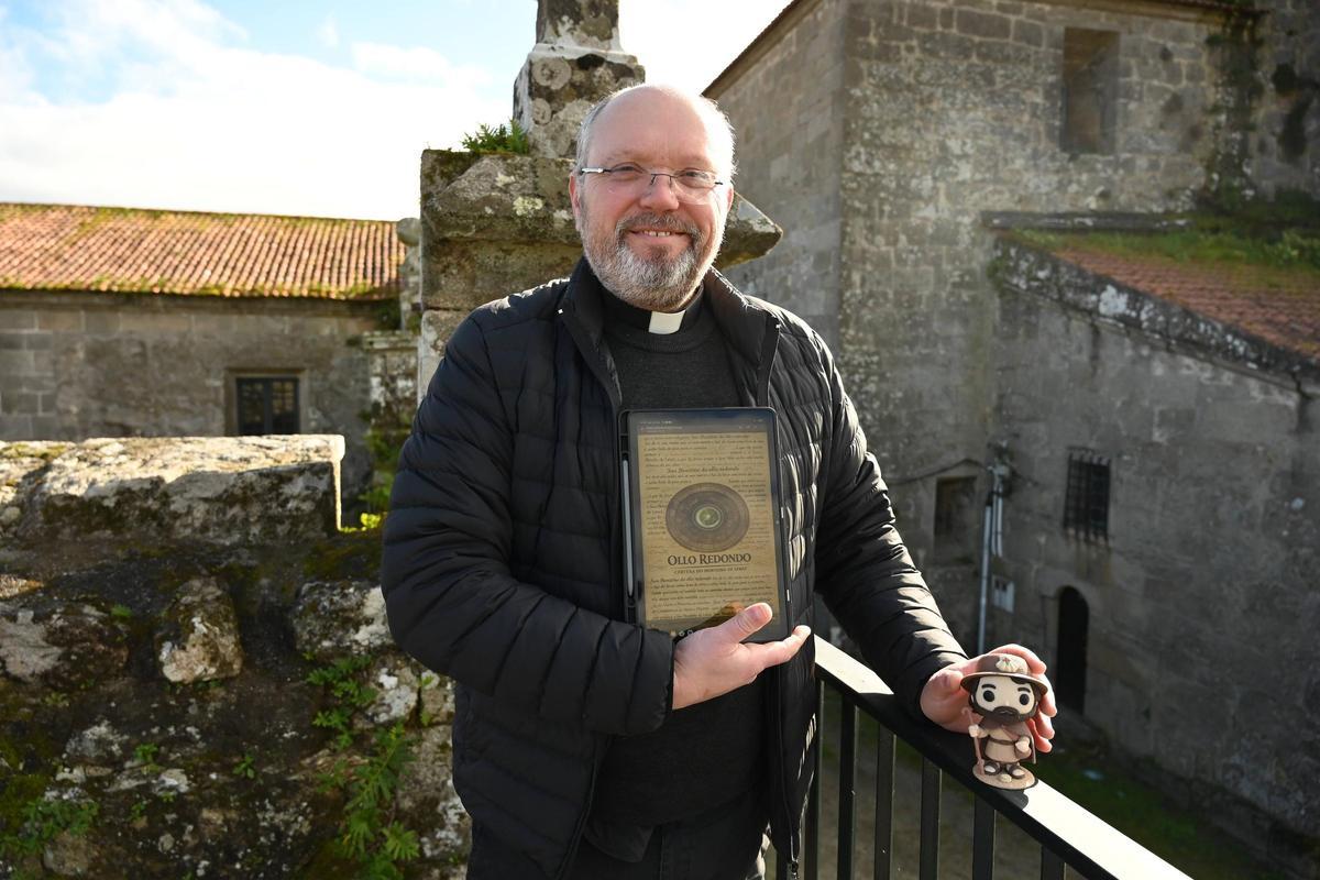 El párroco, Manuel Chouciño, con el muñeco Funko del Santiago Peregrino que lanza la parroquia. También muestra la etiqueta de la nueva cerveza, "Ollo Redondo".