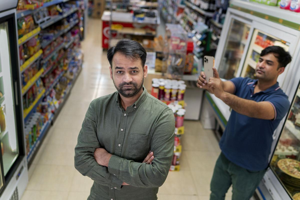 Rustem  posa en la entrada del super junto a su hermano Qasem