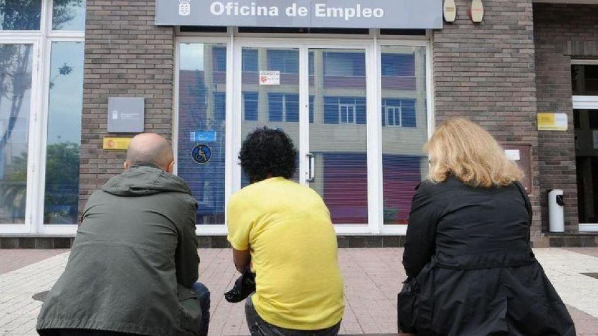 Tres personas esperan a la entrada de una oficina pública de empleo de Canarias