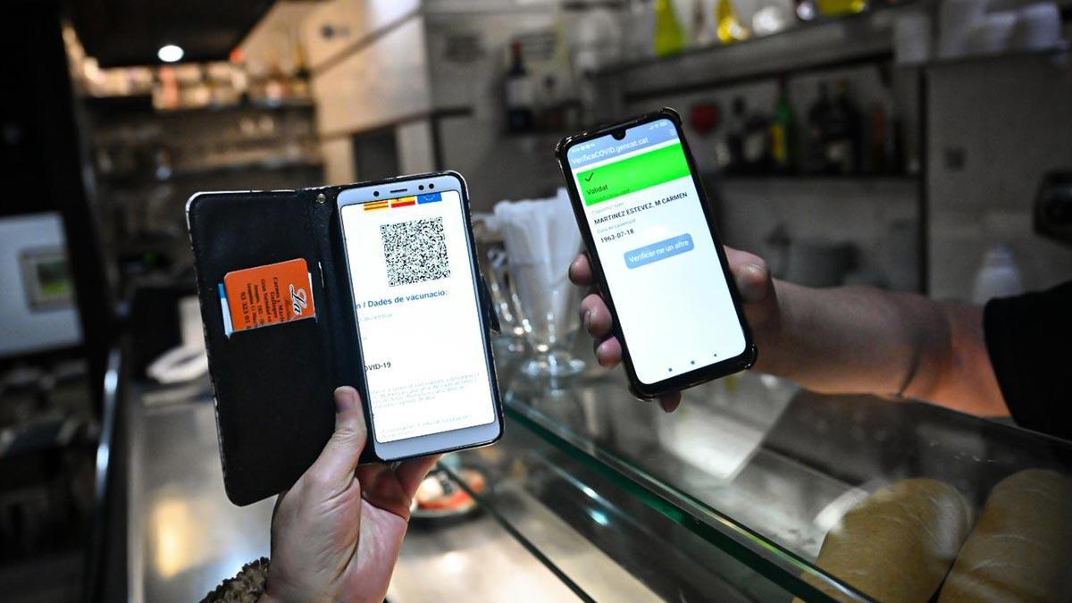El pasaporte covid de una clienta de un bar y la aplicación para validarlo, en un local del Eixample de Barcelona.