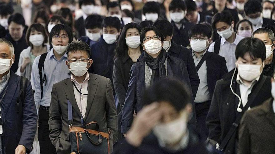 Japoneses circulando con mascarillas por las calles de Tokio.