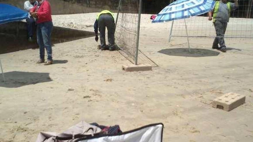 Los operarios instalan el vallado en la playa.