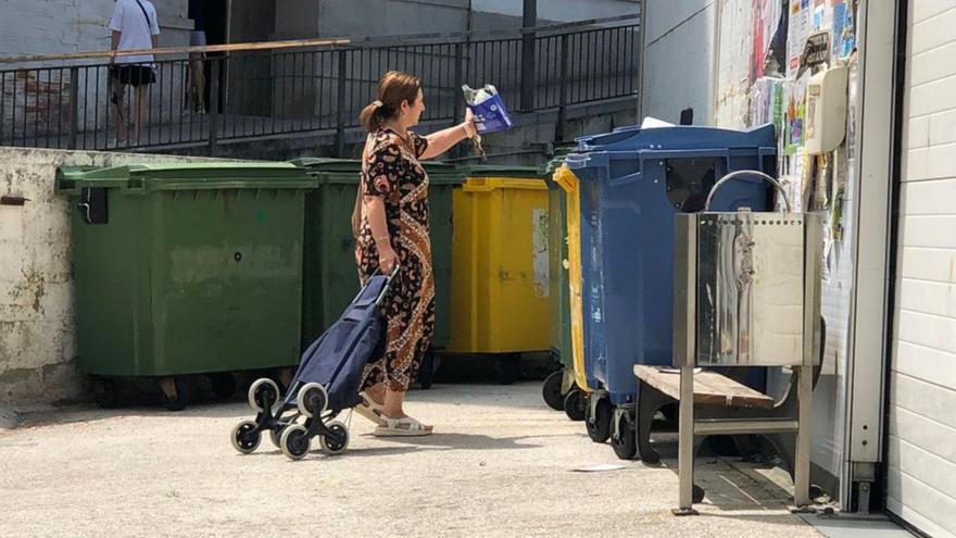 Una mujer depositando basura en un contenedor junto al mercado