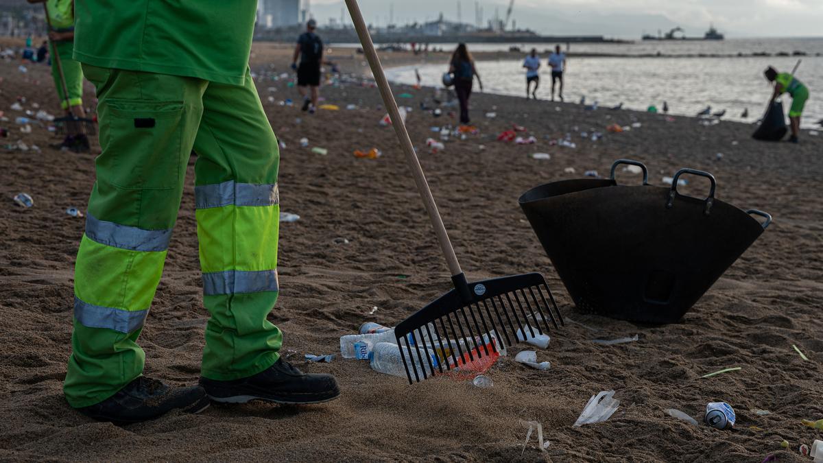 Trabajadores municipales limpian la playa de la Barceloneta tras un botellón, el pasado julio