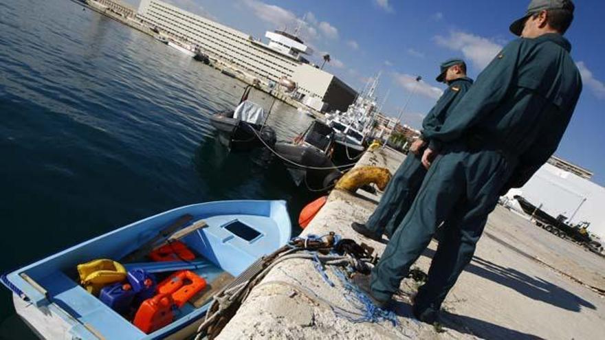 Dos agentes del Servicio Marítimo de la Guardia Civil custodian la patera interceptada esta madrugada cerca de la costa de Torrevieja en la que viajaban ocho inmigrantes de la zona del Magreb.