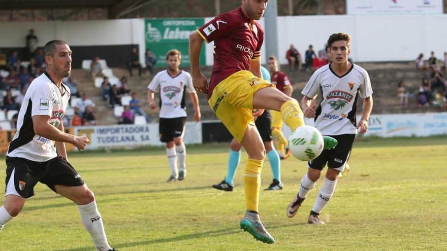 Javi Sánchez trata de controlar el balón entre dos jugadores del Tudelano.