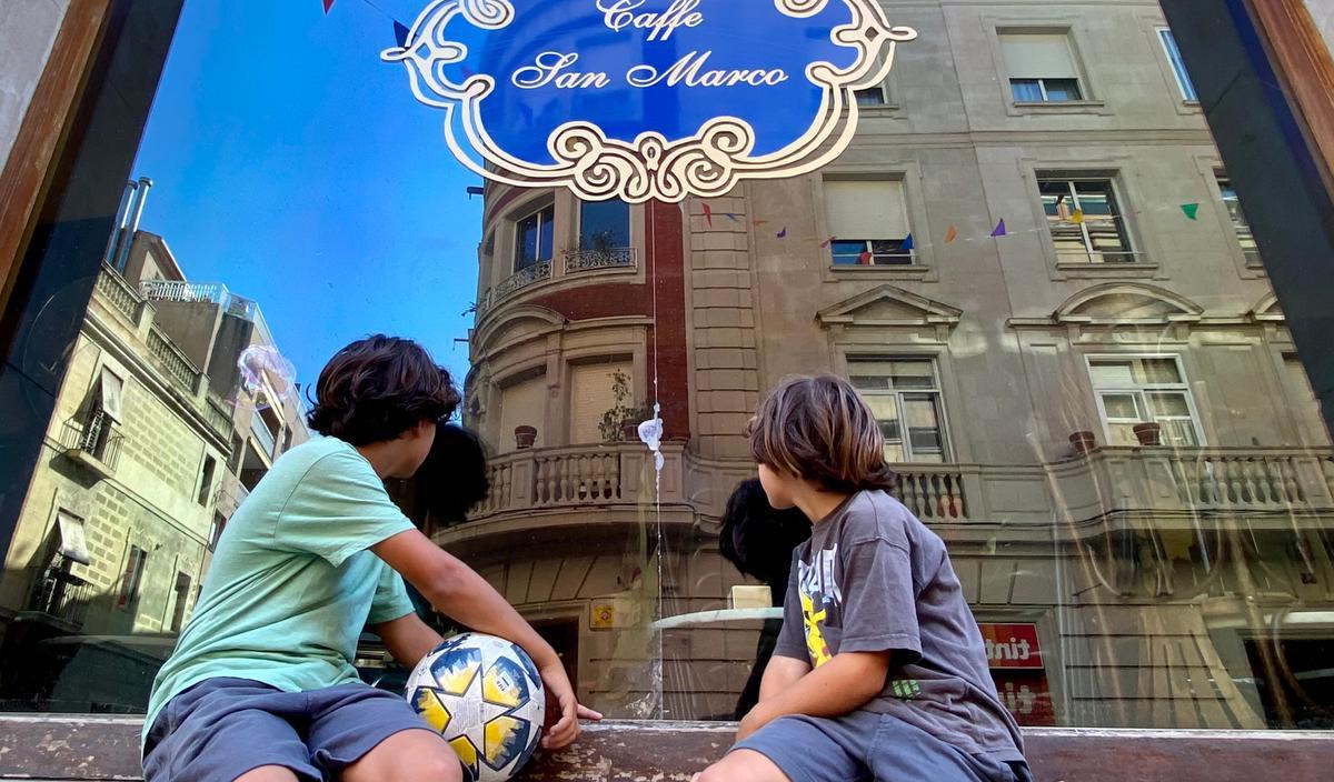 Un par de chavales del barrio observan el interior del café, cerrado al público desde hace unas semanas