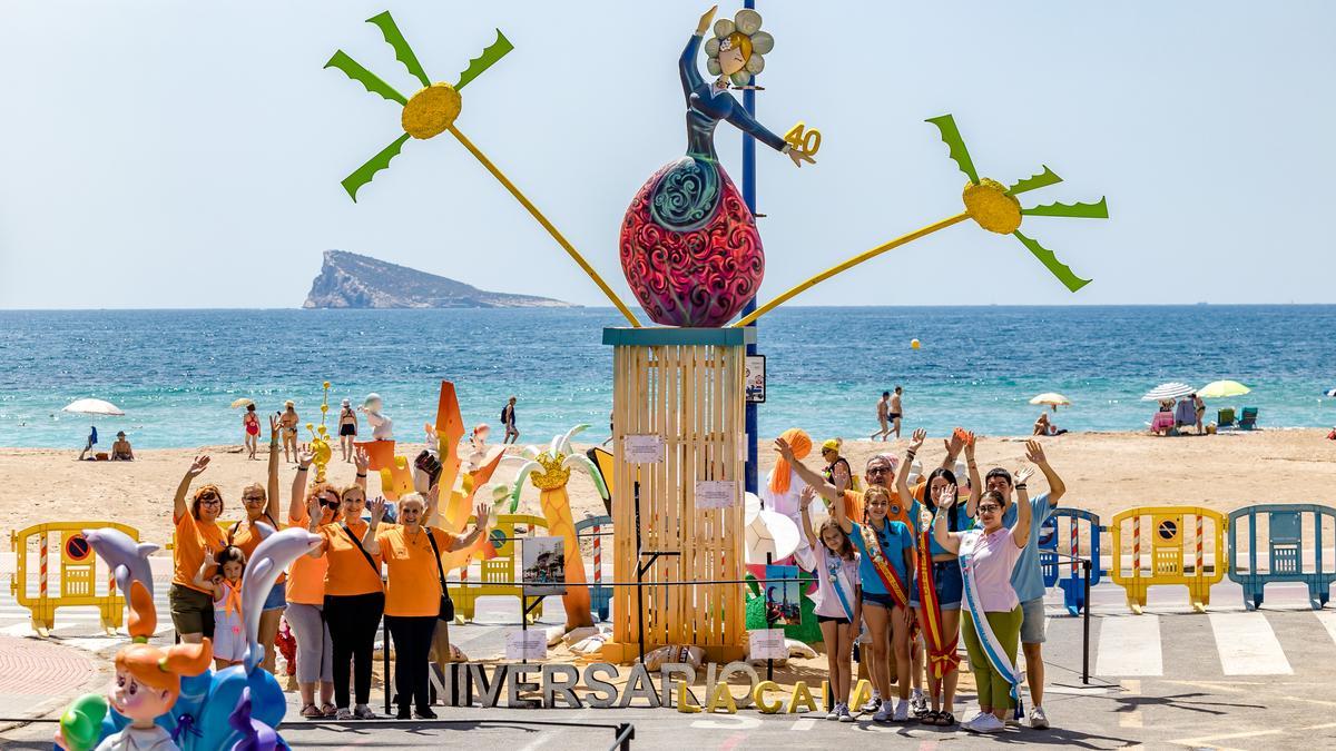 Algunos de los miembros de la Hoguera La Cala posan junto a sus monumentos, con la isla de Benidorm al fondo.