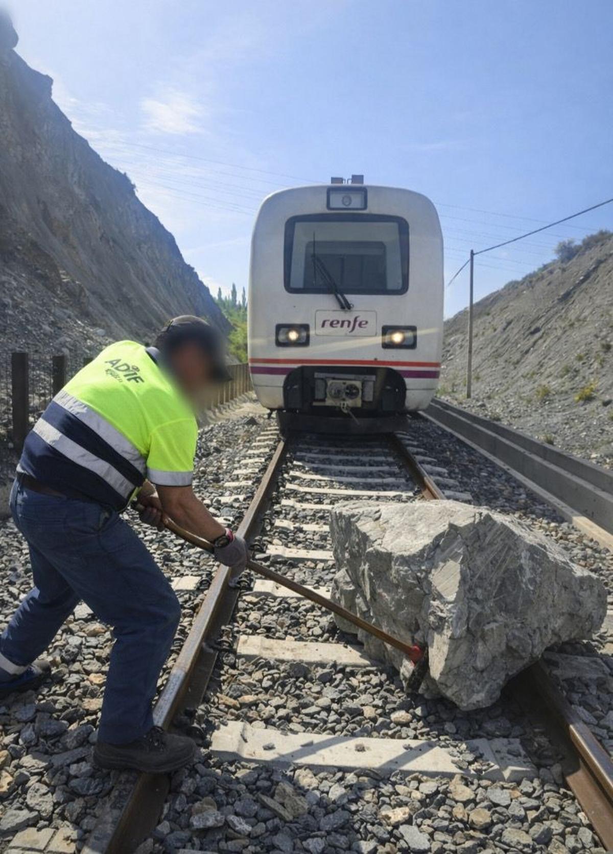 Un operario trabaja para retirar la roca de la vía.