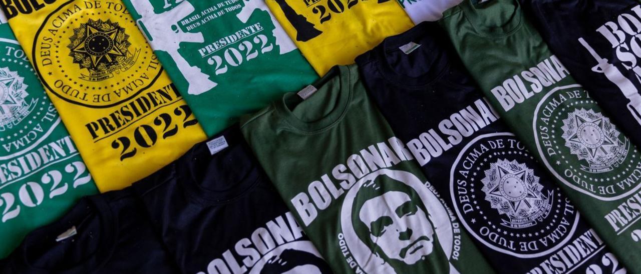 Camisetas con el rostro y el nombre de Bolsonaro entre fusiles de asalto en una calle de Brasilia, este lunes.