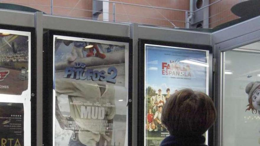 Una mujer observa la cartelera de un cine gallego. la opinión