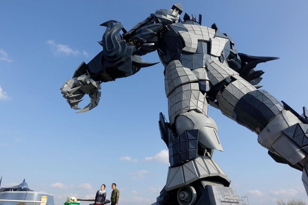 Staff members stand underneath a giant robot ...