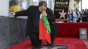 El cineasta mexicano Guillermo del Toro besa una bandera mexicana arrodillado en su recién descubierta estrella del Paseo de la Fama de Hollywood, en Los Ángeles (California, EEUU), este martes.