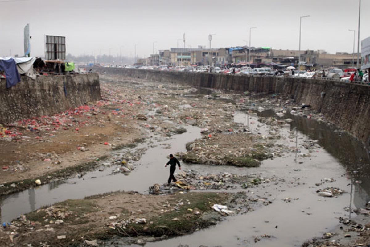 Un home travessa un riu contaminat a Kabul (Afganistan).