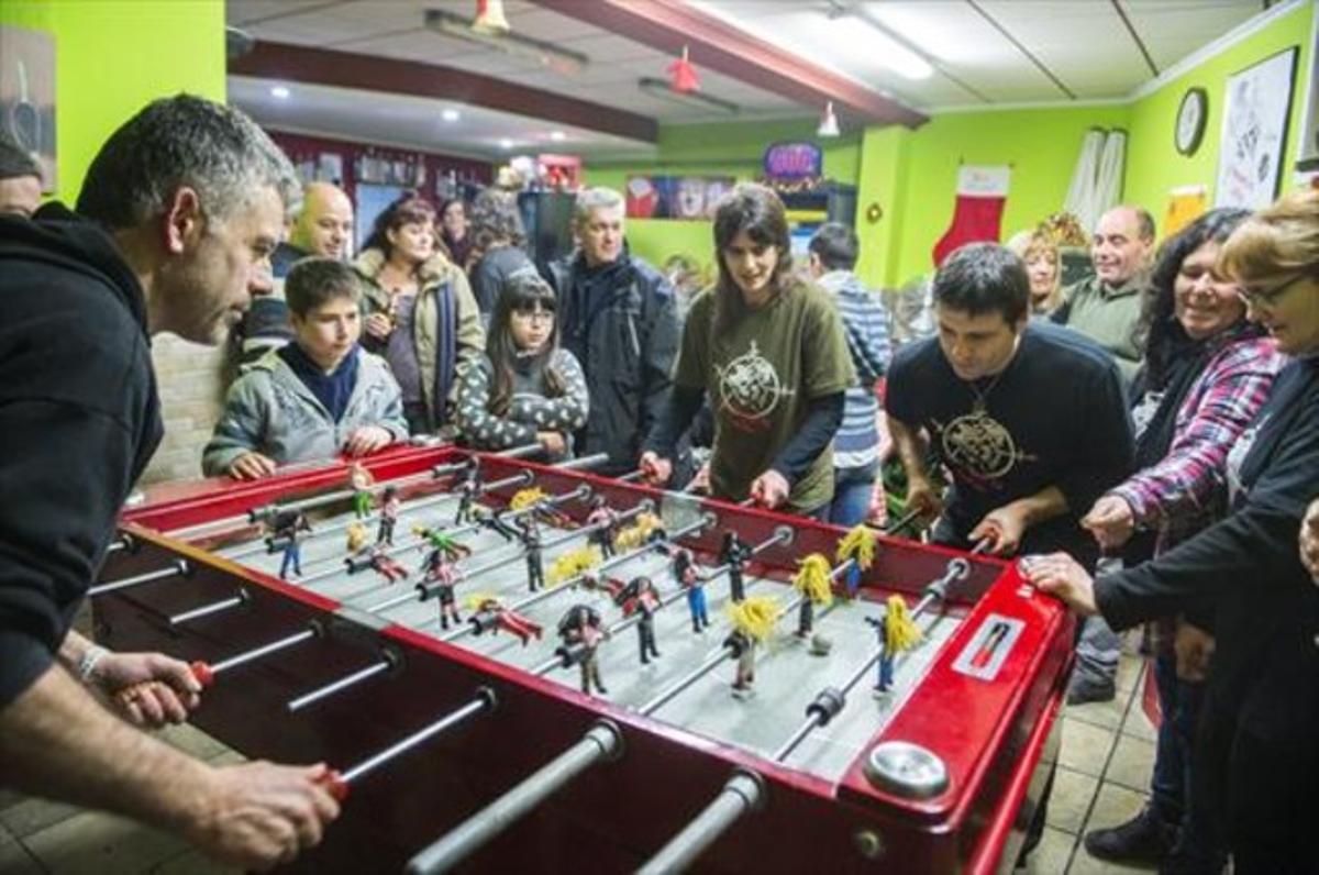 Habituals del bar El Jardí de Ciutat Meridiana, amb el futbolí tunejat en què els jugadors són músics heavies.