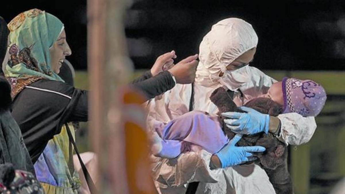 Una integrante de   un equipo de rescate sostiene a un niño, en Pozzalo (Sicilia).