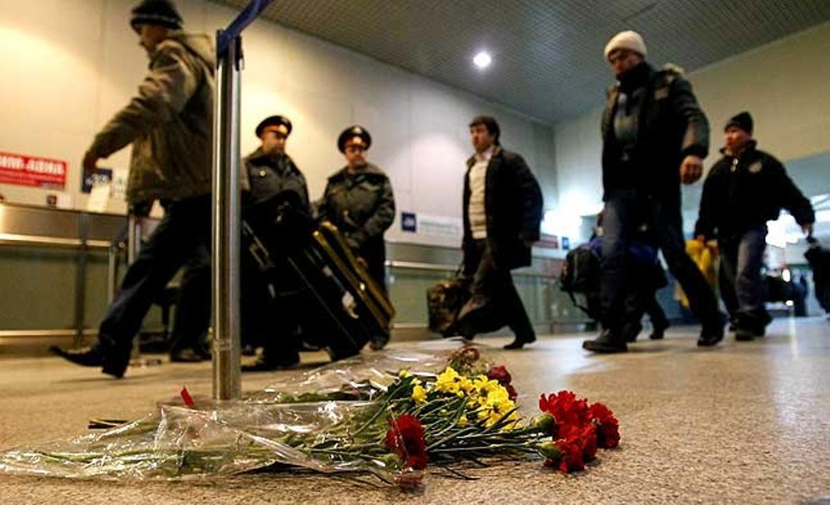 Passatgers caminen a prop de les flors que reposen al terra de l’aeroport Domodedovo de Moscou (Rússia), en memòria dels morts per l’explosió de dilluns que va provocar un terrorista suïcida.