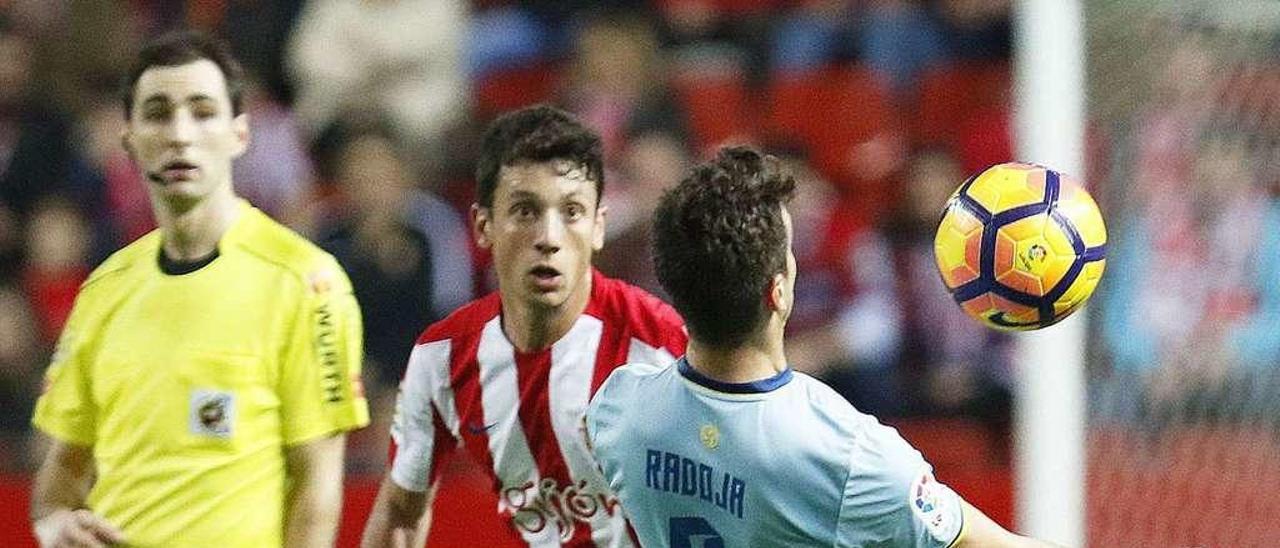 Radoja controla el balón con el pecho ante un rival y el árbitro, ayer en El Molinón. // LNE