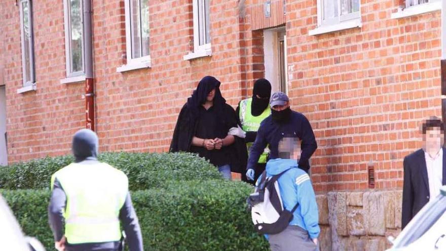 El detenido en la calle de Grijalba sale de su domicilio con el rostro cubierto y escoltado por dos agentes.