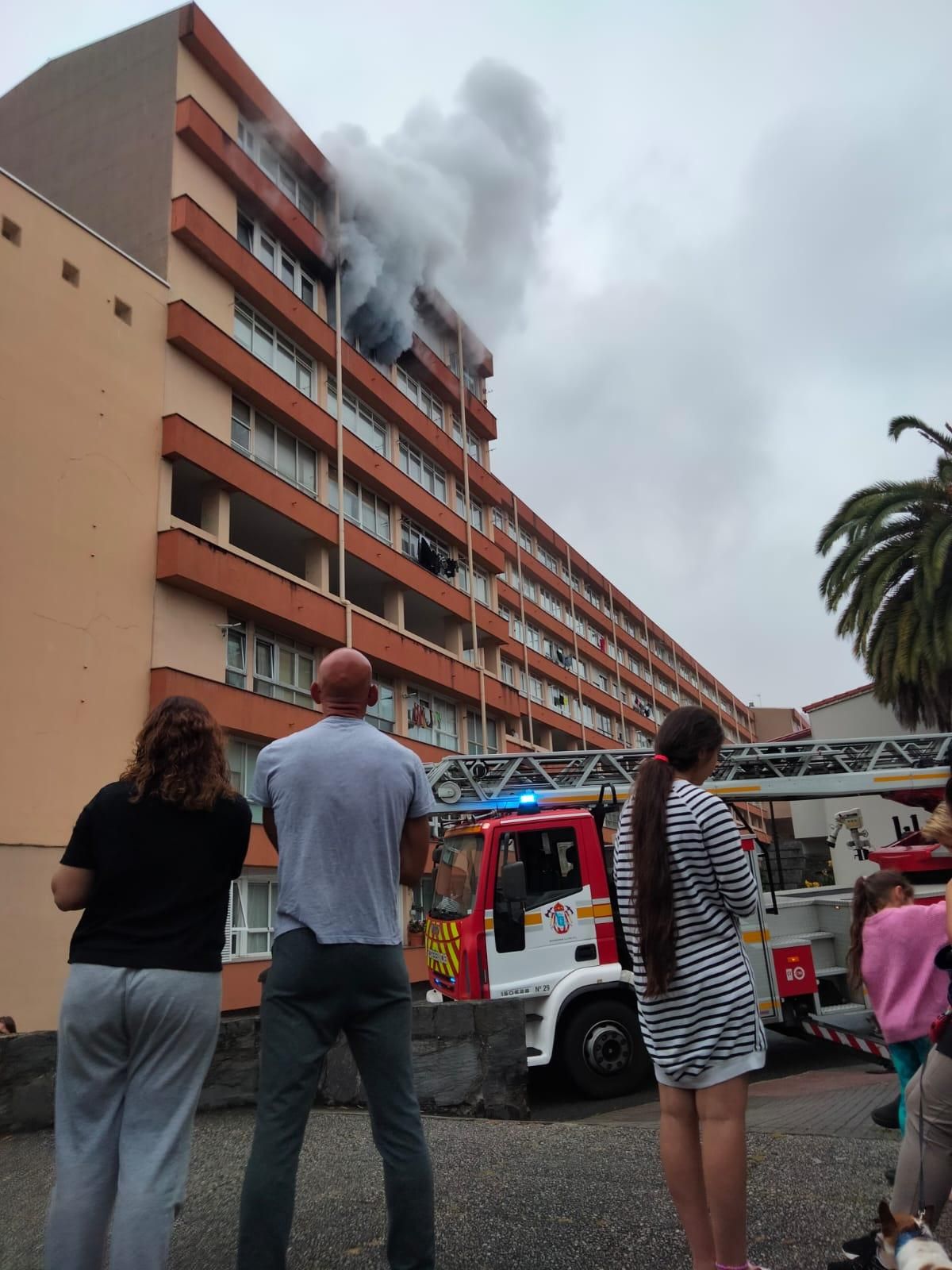 Ciudadanos, pendientes de la intervención de los Bomberos por un incendio en una vivienda del Barrio de las Flores, en la calle Camelias.