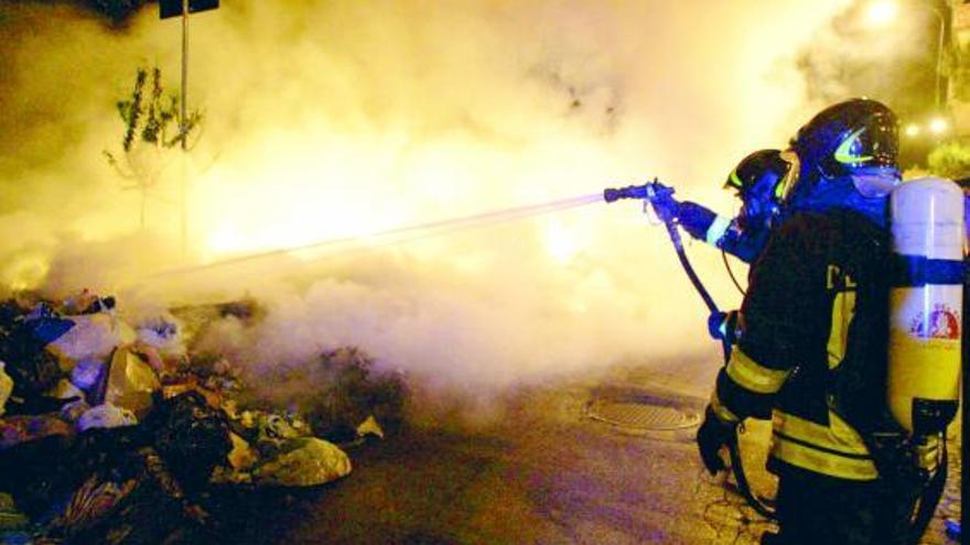 Bomberos tratan de extinguir las llamas que salen de una pila de basura incendiada por napolitanos hastiados.