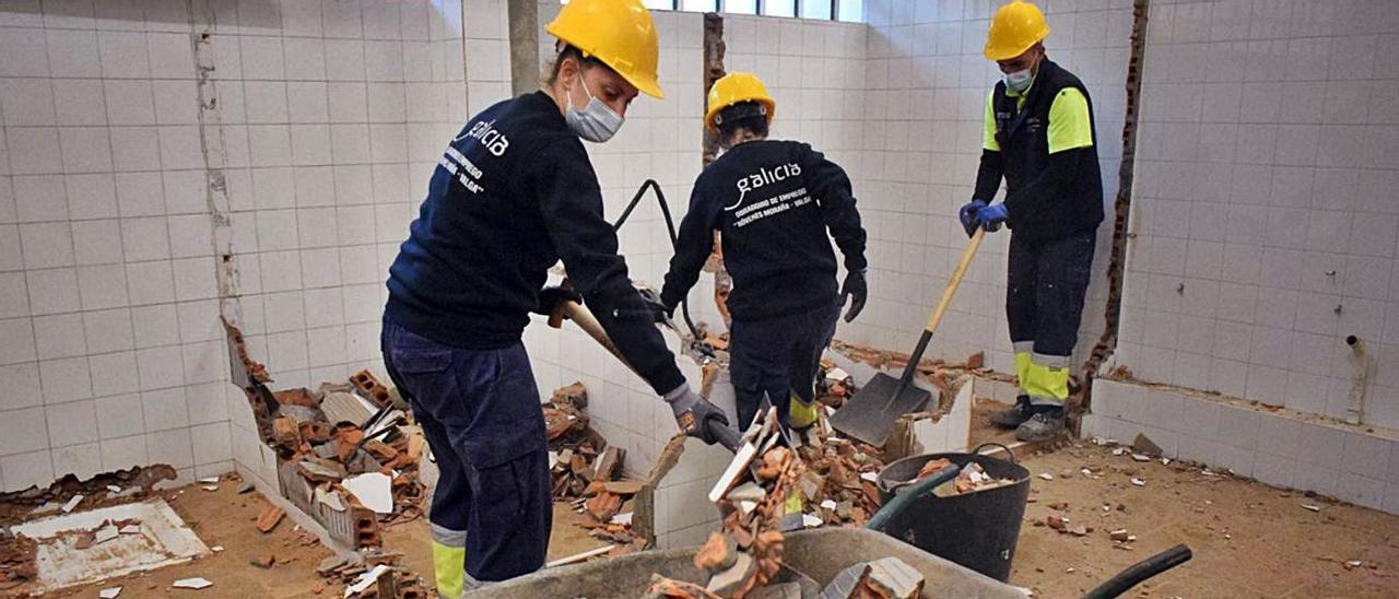 Los alumnos derriban los aseos del pabellón de Beiro antes de instalar otros nuevos.