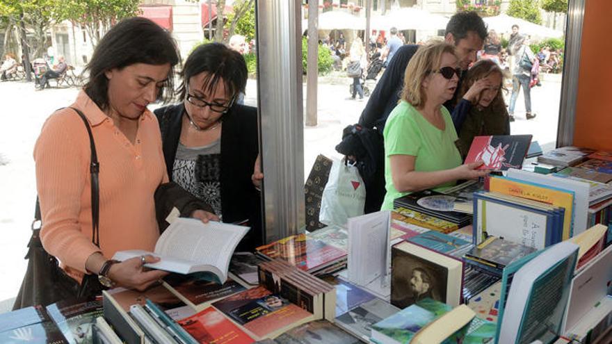 Varias personas observan algunos de los libros de uno de los puestos. // Rafa Vázquez