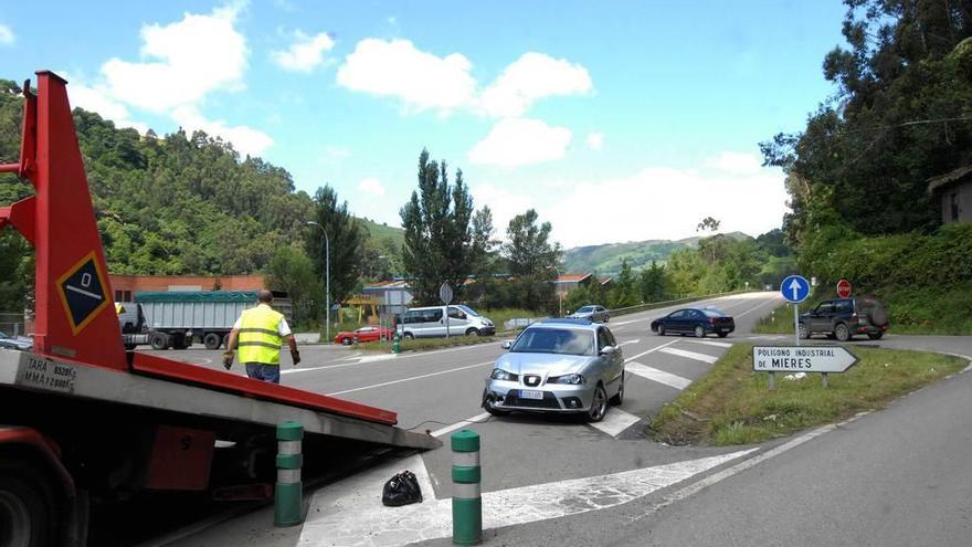 Una grúa atiende a un coche implicado en un accidente de tráfico en el enlace a Fábrica de Mieres.