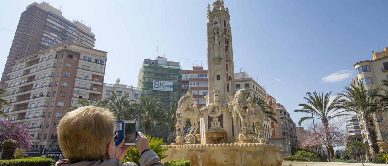 Una mujer fotografía la fuente de Luceros, que está pendiente de las obras de restauración