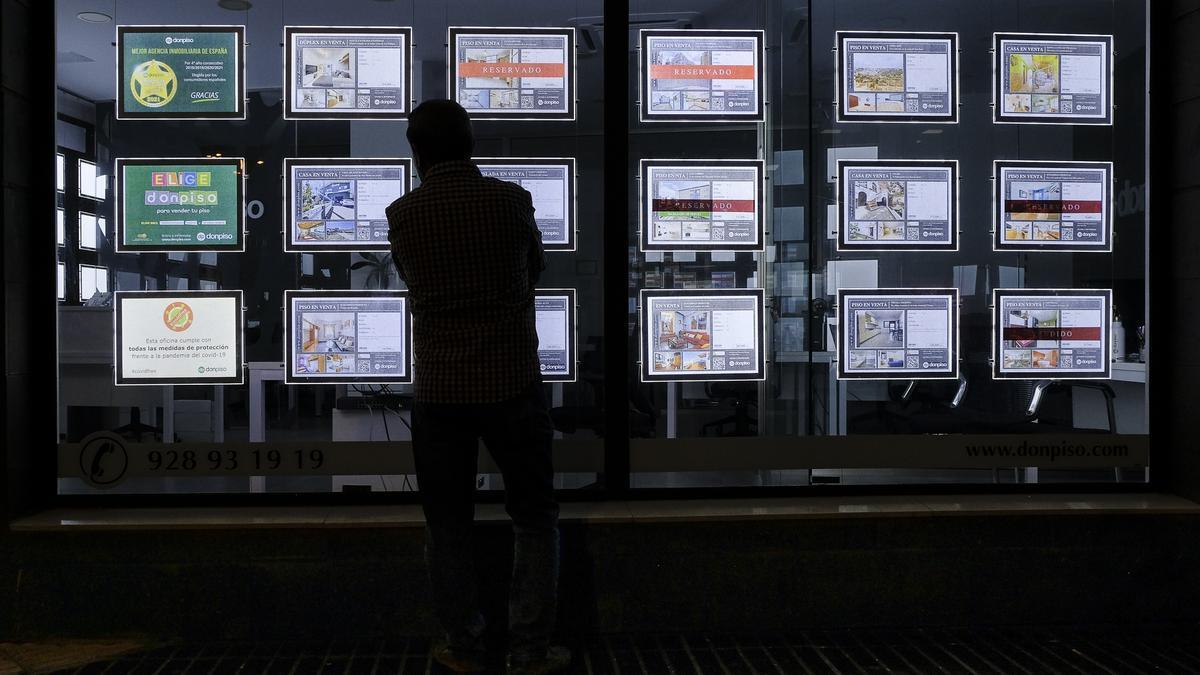 Un hombre consulta las ofertas de vivienda en el escaparate de una inmobiliaria