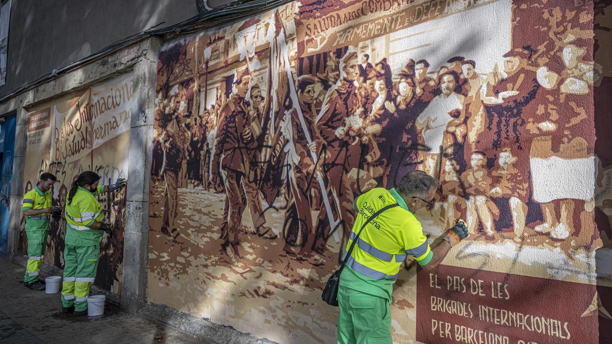 Trabajadores de la limpieza borran los mensajes pintados en el mural de recuerdo a las Brigadas Internacionales, en Barcelona.