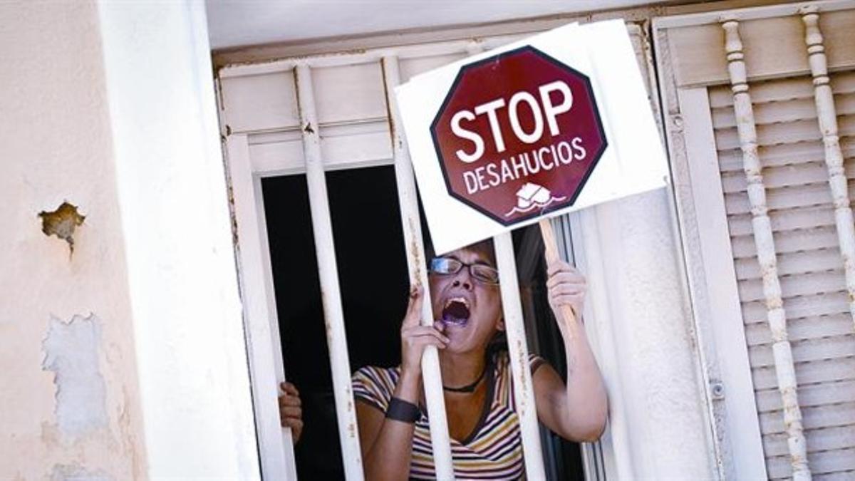 Una mujer protesta desde la ventana de una casa durante un acto de desahucio, en junio del 2011, en Madrid.