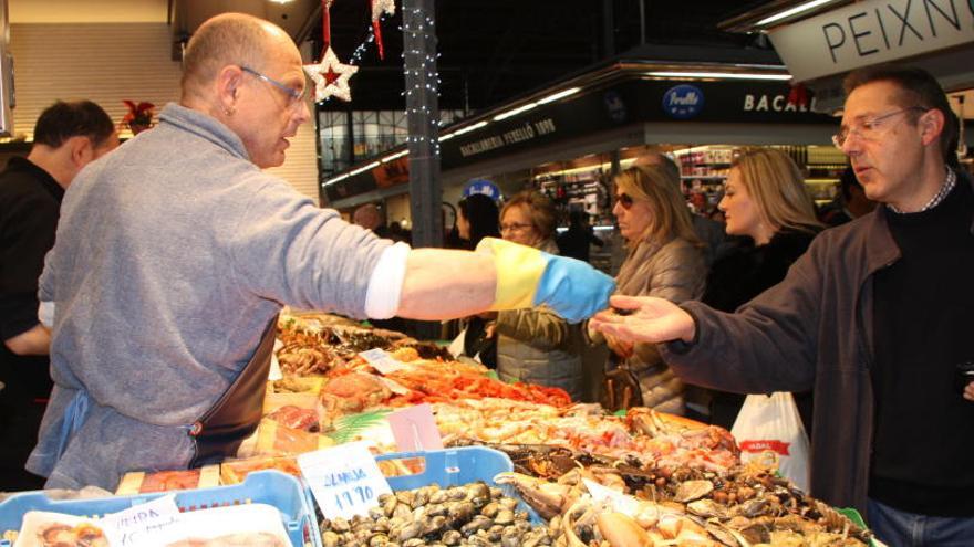 Un botiguer d&#039;una parada de marisc lliura la compra a un client en un mercat municipal