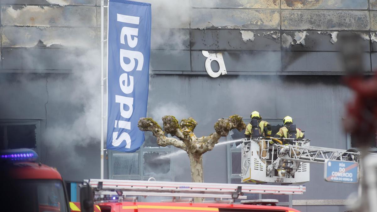 Una veintena de bomberos sofocan el fuego que causó dos heridos en un desguace del polígono de O Ceao, en Lugo.