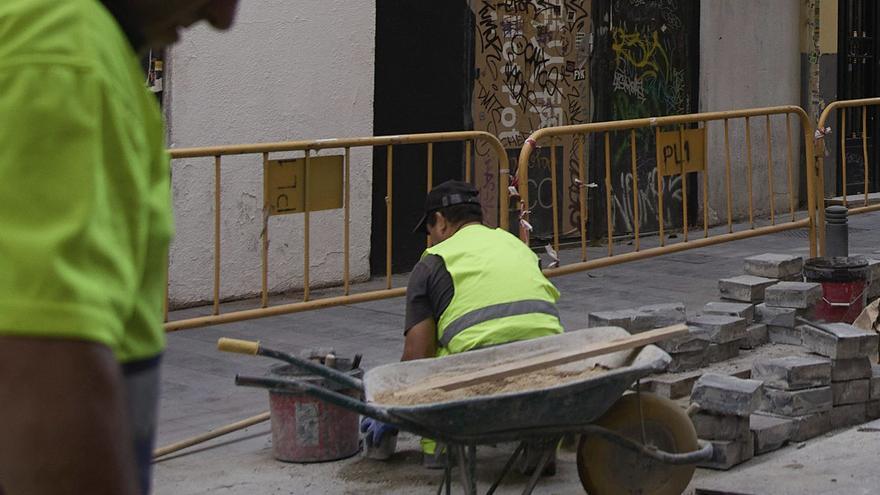 Dos trabajadores arreglan una acera. | Jesús Hellín