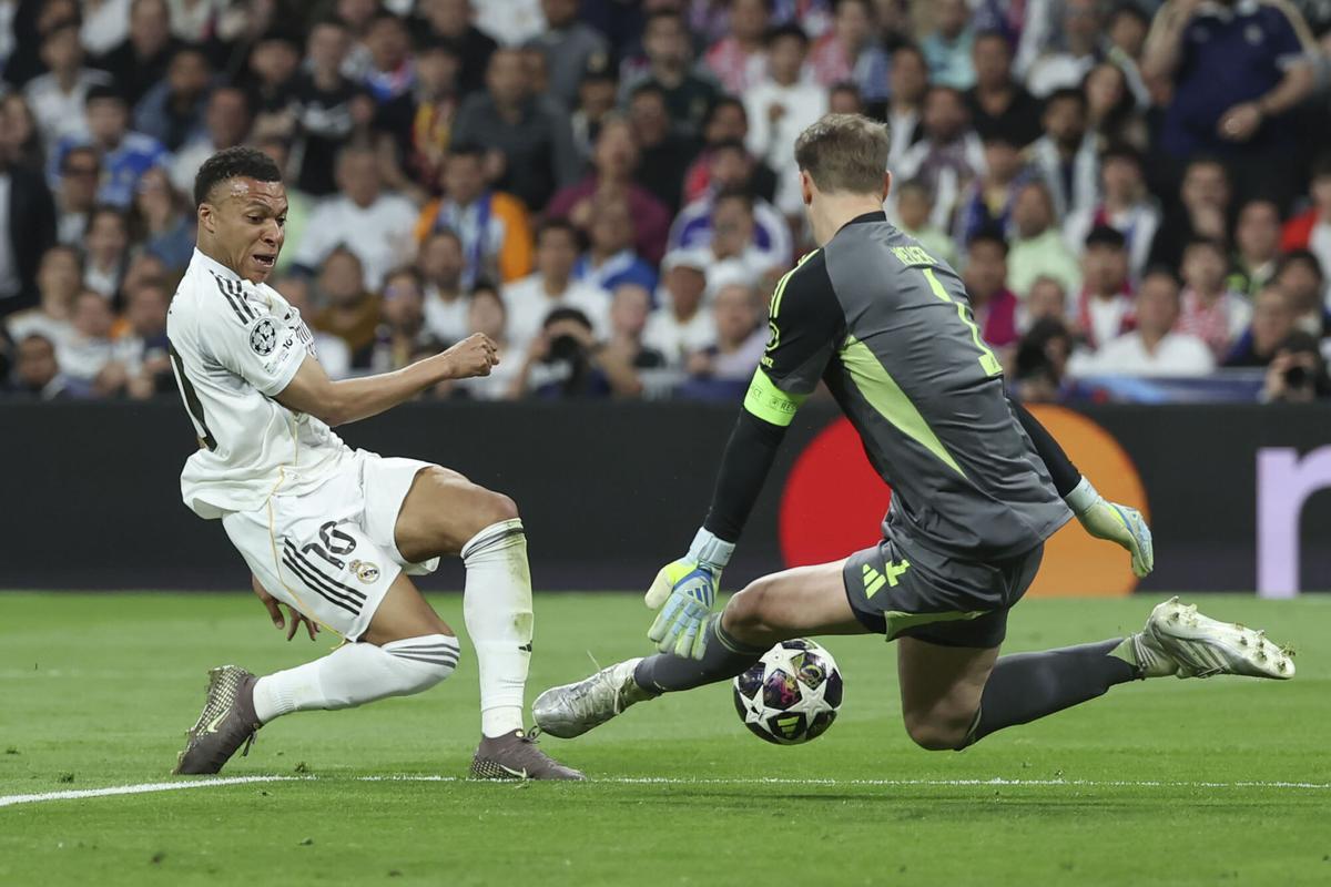 El delantero francés del Real Madrid Kylian Mbappé (i) disputa un balón ante el portero del Bayern Manuel Neuer durante el encuentro correspondiente a la ida de los cuartos de final de la Liga de Campeones que disputan este martes Real Madrid y Bayern Munich en el estadio Santiago Bernabéu, en Madrid. EFE/ Kiko Huesca