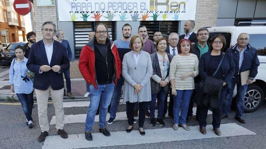 Asistentes a la reunión posan bajo una pancarta en defensa del plan de vías.