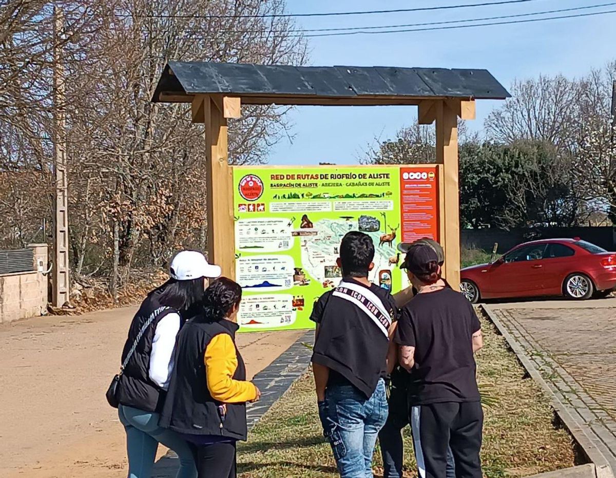 Varios jóvenes observan un cartel en Sarracín. | Chany Sebastián