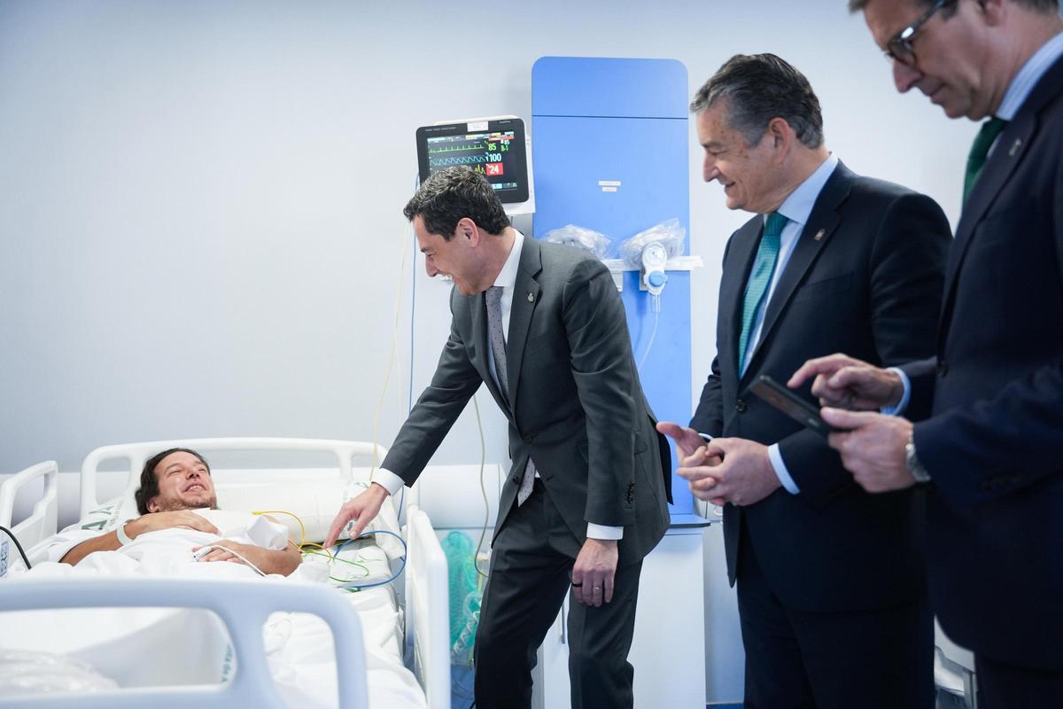 El presidente de la Junta, Juanma Moreno, saluda a un paciente ingresado en el Virgen del Rocío en Sevilla.