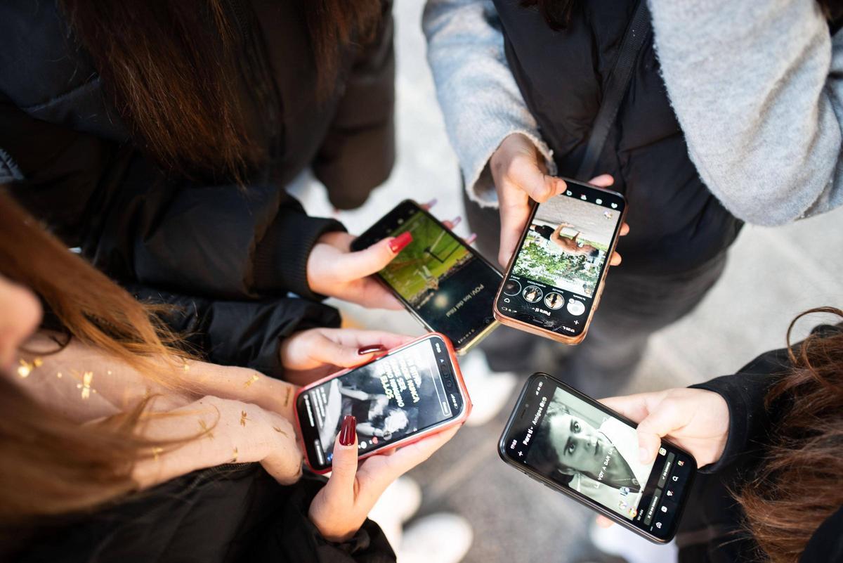 Noies, consultant les xarxes socials amb els seus telèfons mòbils