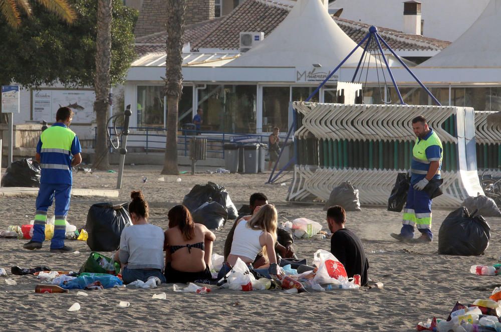 Los operarios de los servicios de limpieza trabajan para dejar la playa en óptimas condiciones tras una larga noche de fiesta en la arena