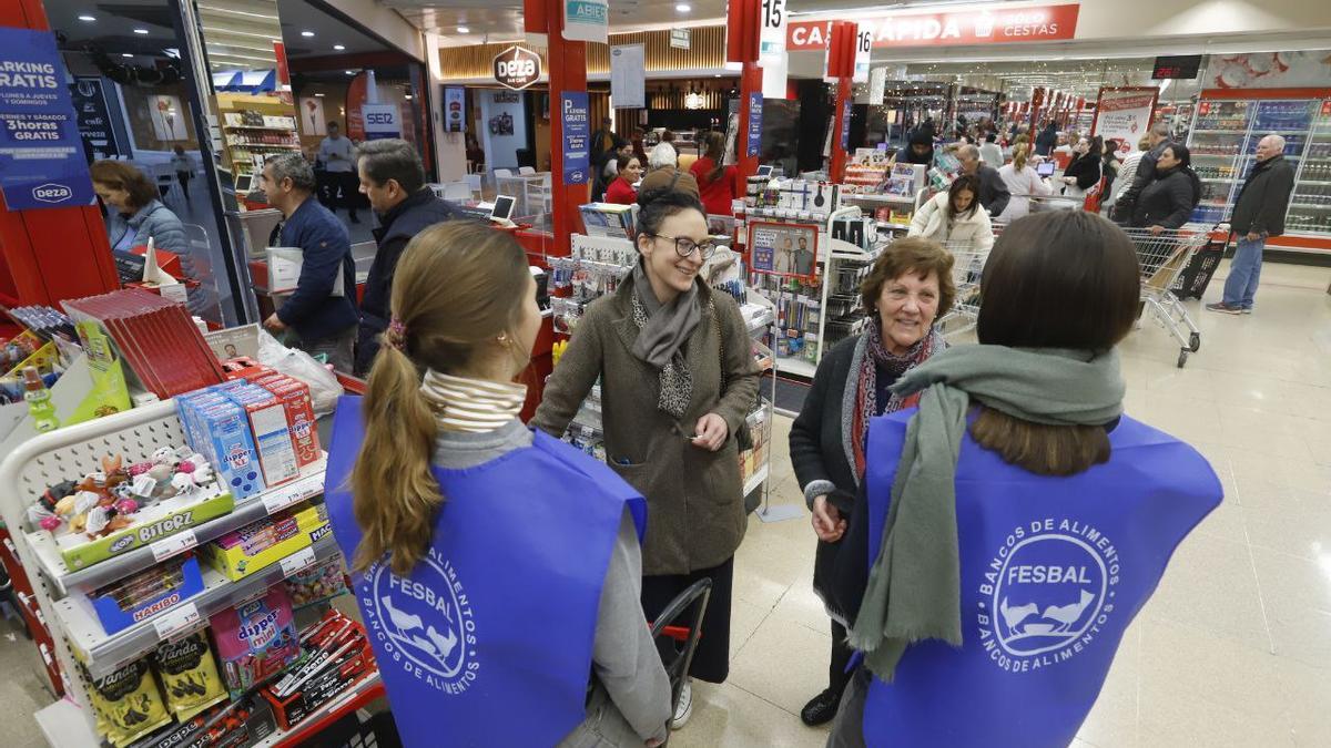 Voluntarios y clientes de un supermercado durante una campaña de recogida del banco de alimentos.