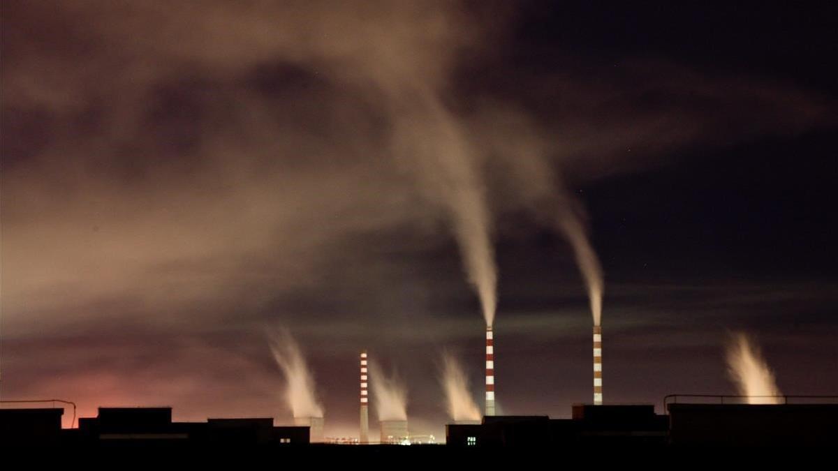 Chimeneas de una planta de energia de carbon emiten humo durante la noche en Changchun en China.