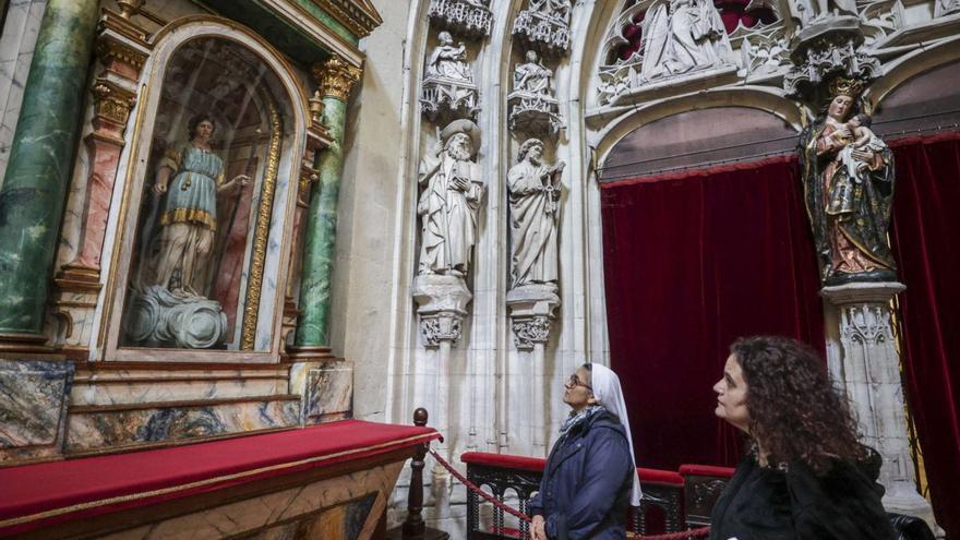 Janeth Aguirre y Lucía Nosti, ayer, contemplando el retablo ubicado a la derecha, tras su restauración. | LNE