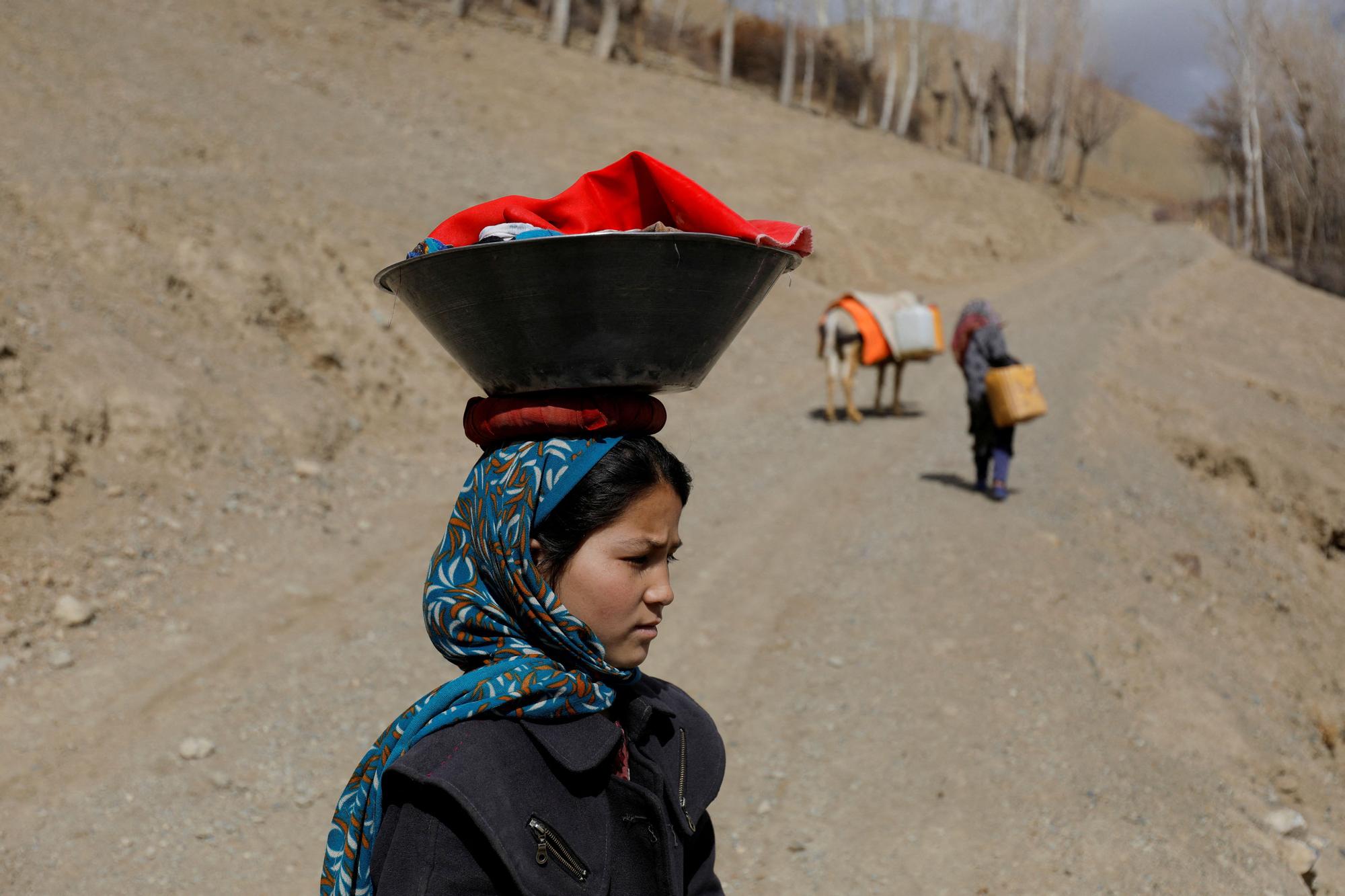 An Afghan girl carries washed clothes on her head in Bamiyan