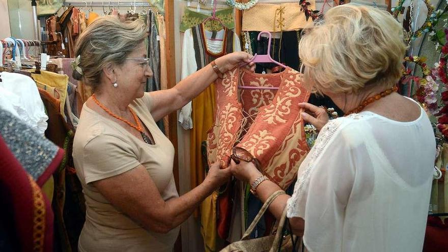 Varias personas examinan un traje medieval en uno de estos comercios especializados en la Feira Franca. // Rafa Vázquez