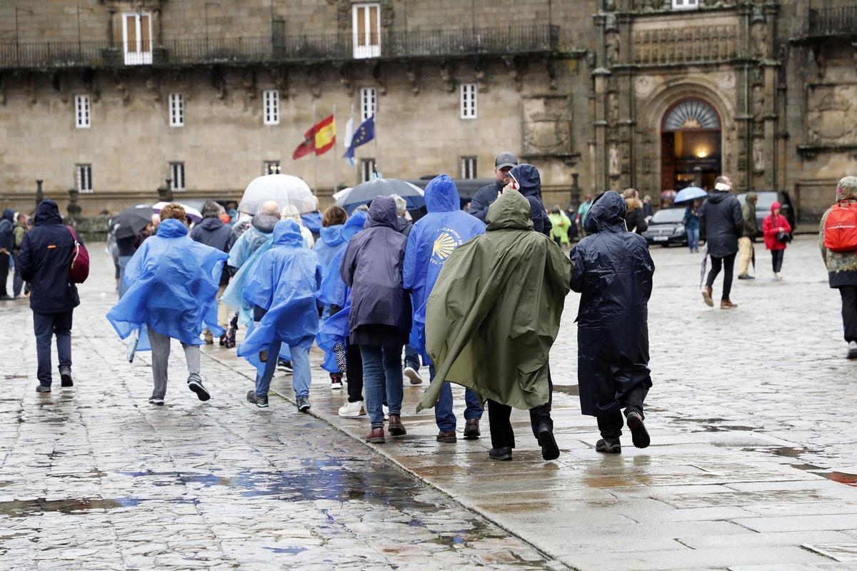 Un grupo de turistas en el Obradoiro ataviados con chuvasqueros por las fuertes lluvias de la borrasca Ciarán