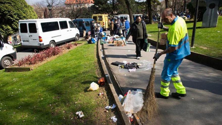 Un operario municipal, el pasado domingo, recogiendo la basura, con las furgonetas aparcadas en el parque.